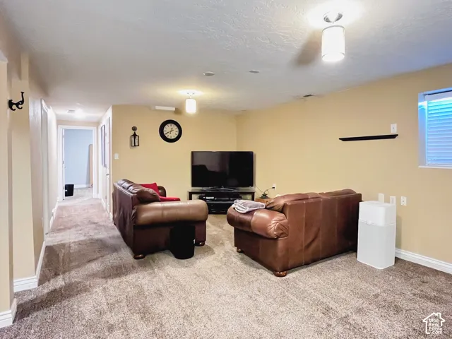Carpeted living area with recessed lighting and a window with blinds