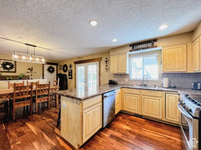 Wood-finish flooring, recessed lighting, and a kitchen island with a stone-finish countertop
