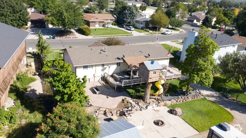 Expansive backyard featuring a concrete patio, grassy areas, and mature trees