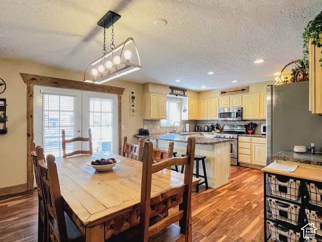 Wood-finish flooring throughout, with a kitchen featuring light wood cabinetry, stone countertops, and stainless steel appliances