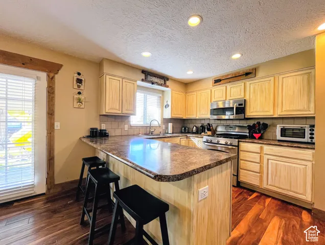 Kitchen featuring wood-finish flooring, recessed lighting, wood cabinetry, stone-finish countertops, and a tile backsplash