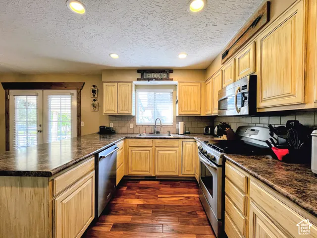U-shaped kitchen featuring wood-finish cabinetry, stainless steel appliances, and wood-finish flooring