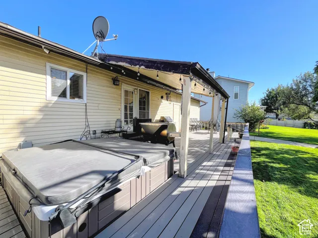 Expansive deck with a covered patio area, built-in hot tub, and direct backyard access