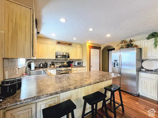 Kitchen featuring recessed lighting, a stainless steel refrigerator, a double basin sink, and wood-finish flooring