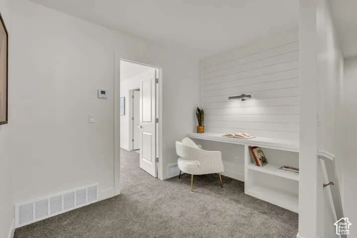 Built-in desk with integrated shelving, shiplap accent wall, and wall-mounted task lighting