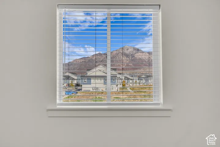 Window with white blinds, offering a backdrop of distant mountains