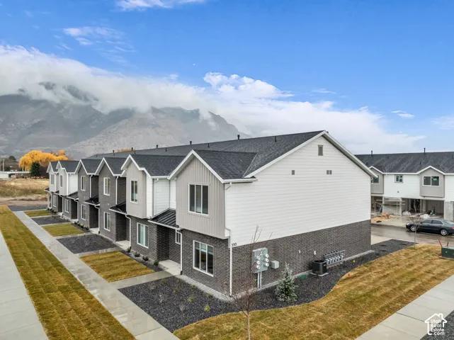 Row of townhomes featuring dark gray brick, light siding, and dark shingle roofs