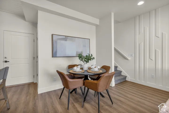 Wood-finish flooring throughout, modern wall paneling, recessed lighting, and a white two-panel interior door