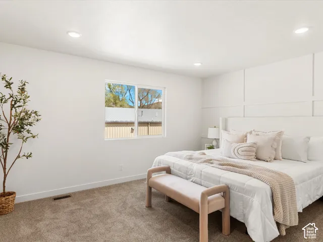 White paneled accent wall, recessed lighting, carpeted flooring, and a large window
