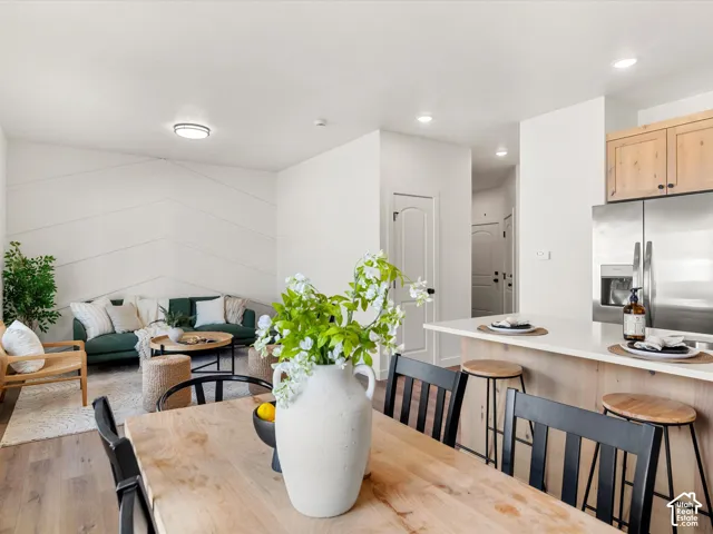 Open-concept living space featuring wood-finish flooring, a kitchen island with seating, stainless steel appliances, and a decorative accent wall
