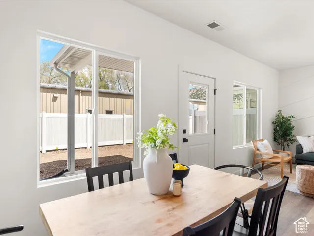 White walls with multiple windows, glass-paneled exterior door, and wood-finish flooring