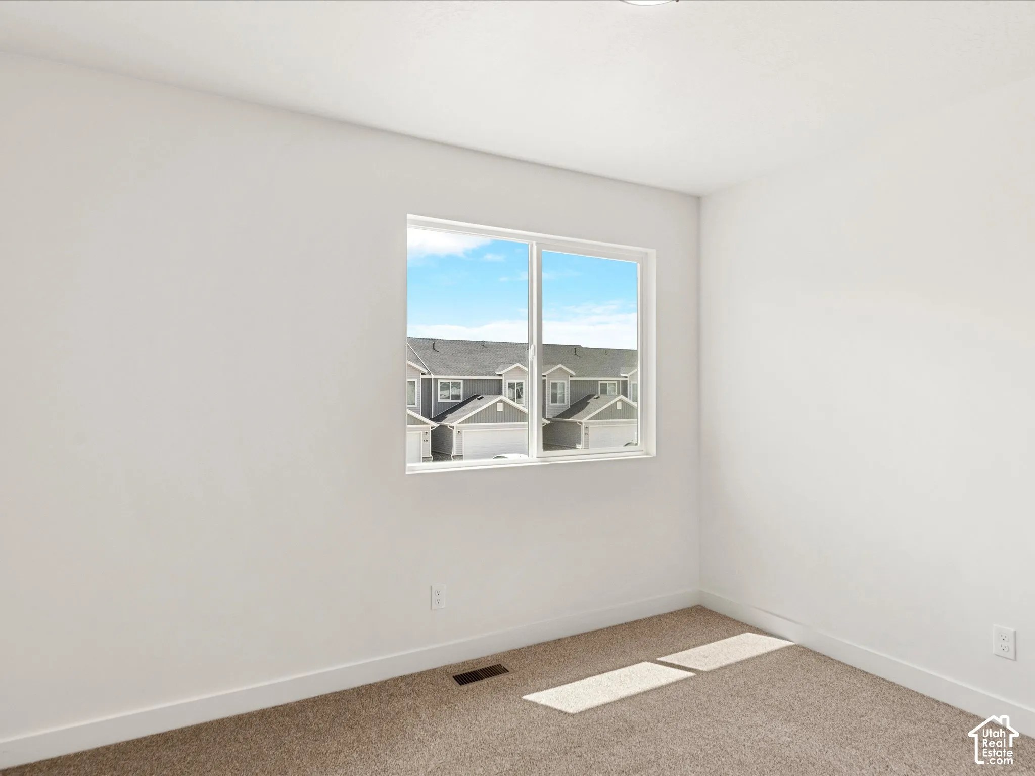 Neutral wall color, wall-to-wall carpeting, white trim, and a window with white framing