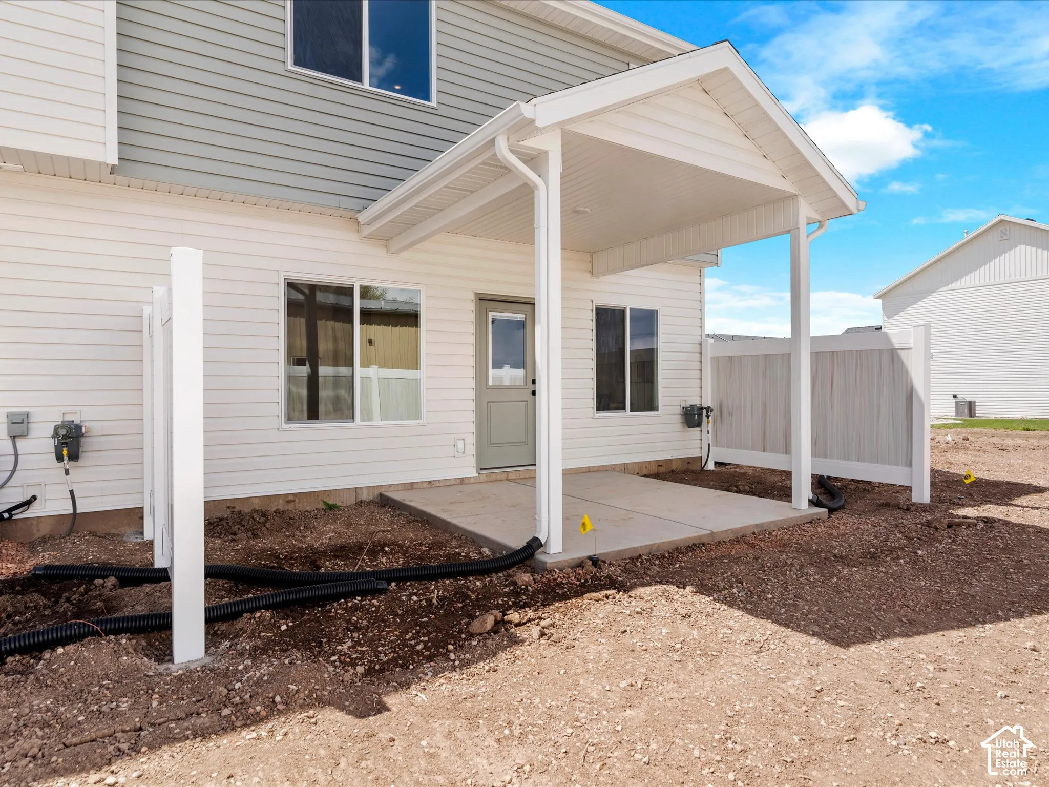 Rear exterior featuring a covered concrete patio, vinyl siding, and a privacy fence