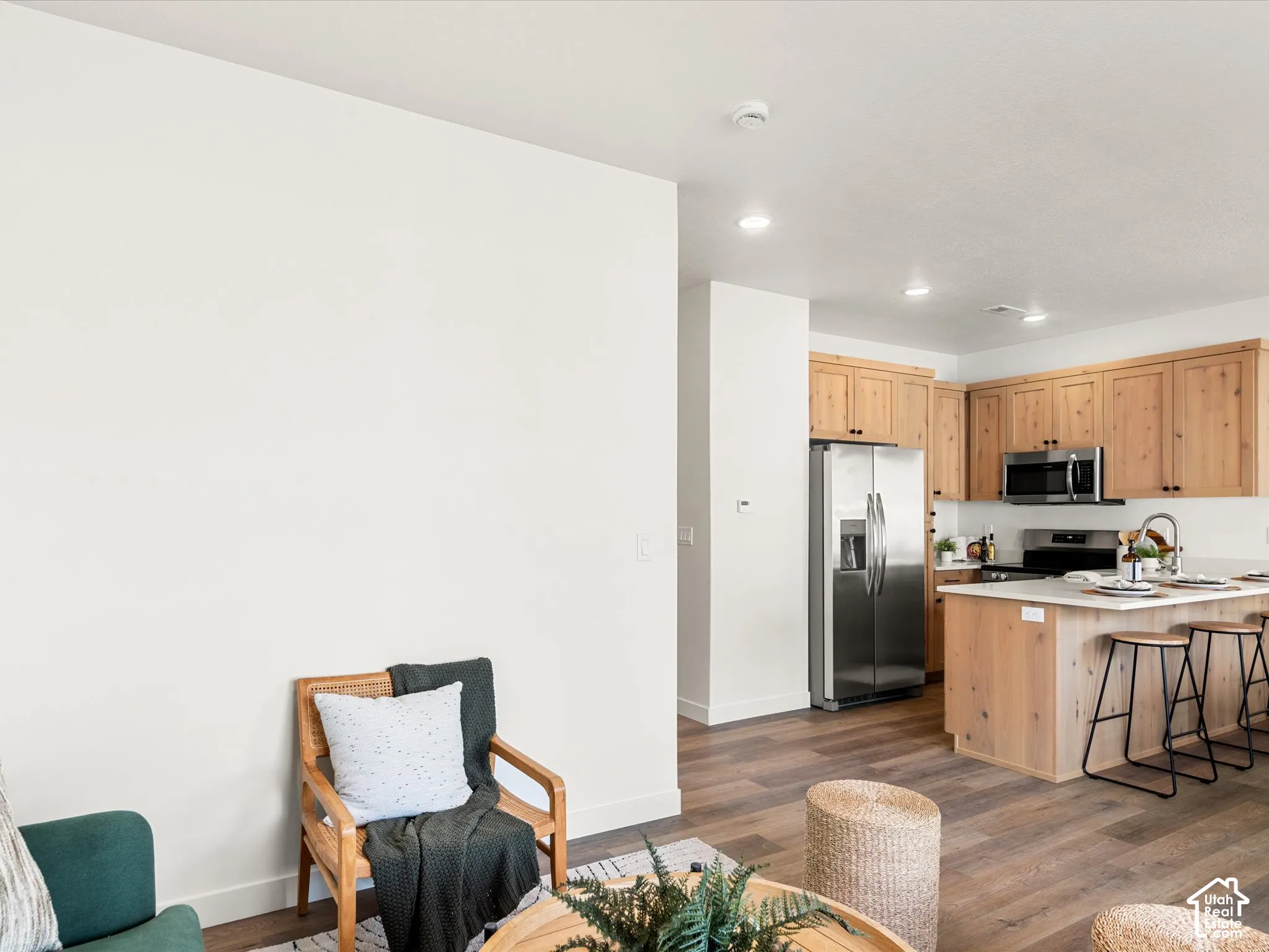 Kitchen featuring wood-finish cabinetry, stainless steel appliances, a center island with seating, recessed lighting, and wood-finish flooring