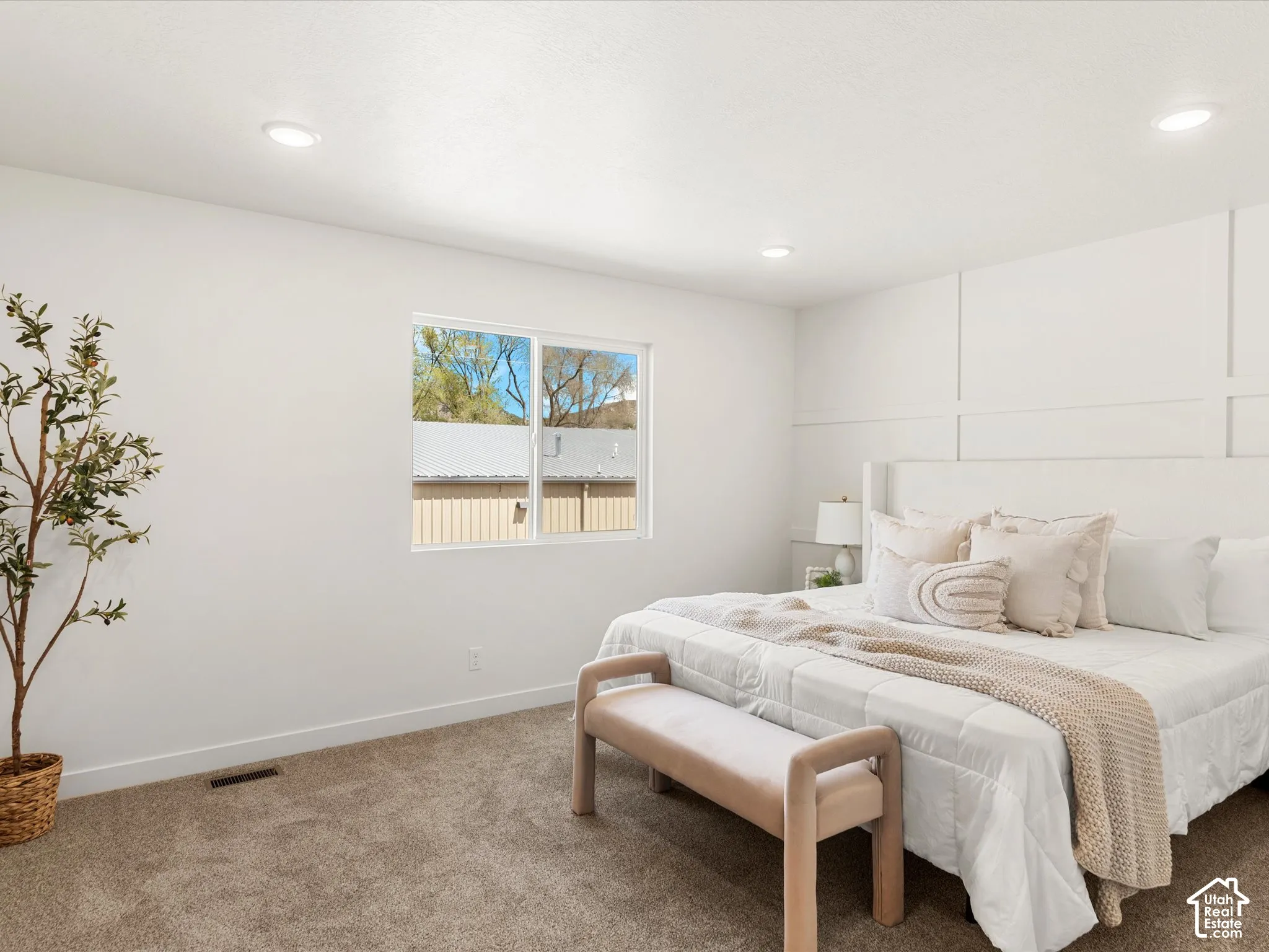 White paneled accent wall, recessed lighting, carpeted flooring, and a large window