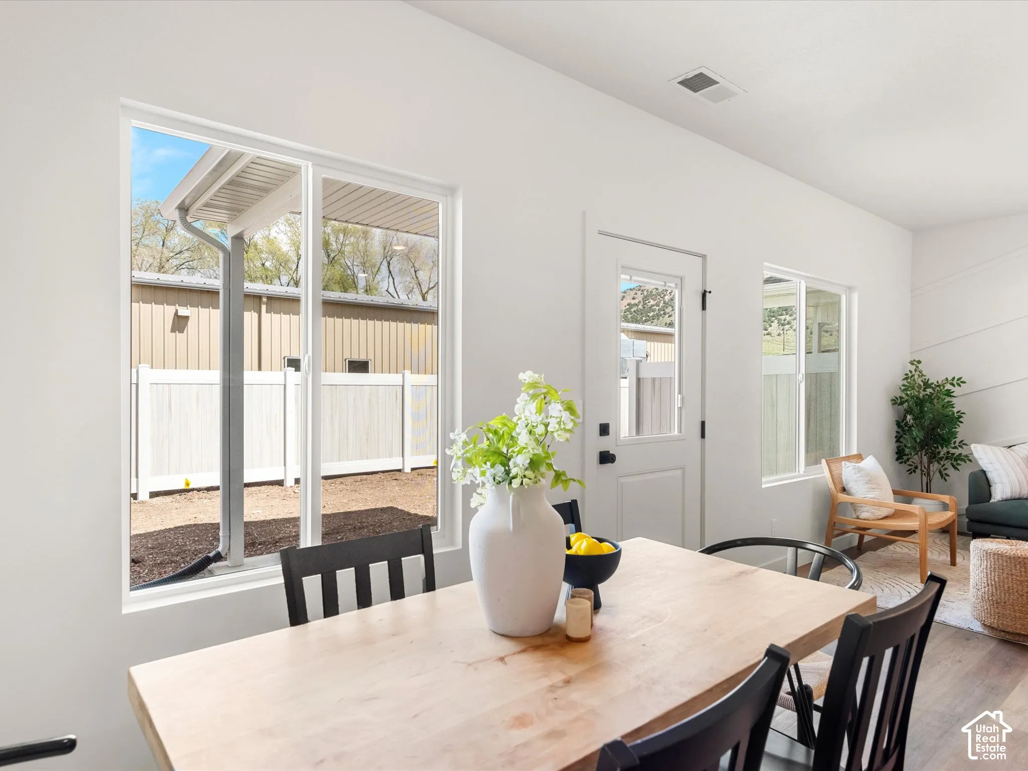 White walls with multiple windows, glass-paneled exterior door, and wood-finish flooring
