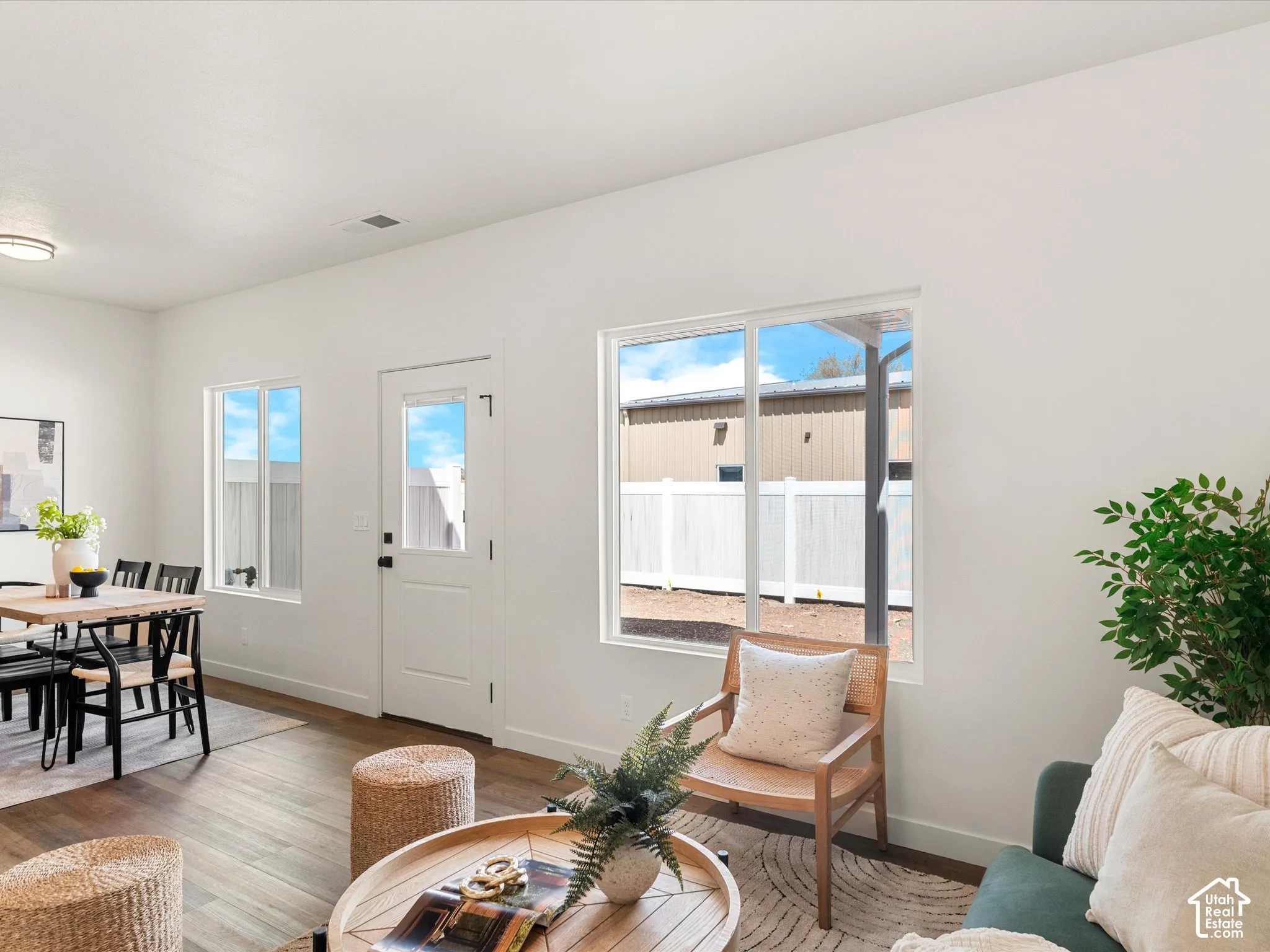 Wood-finish flooring throughout, white walls, multiple windows, and a glass-paneled exterior door