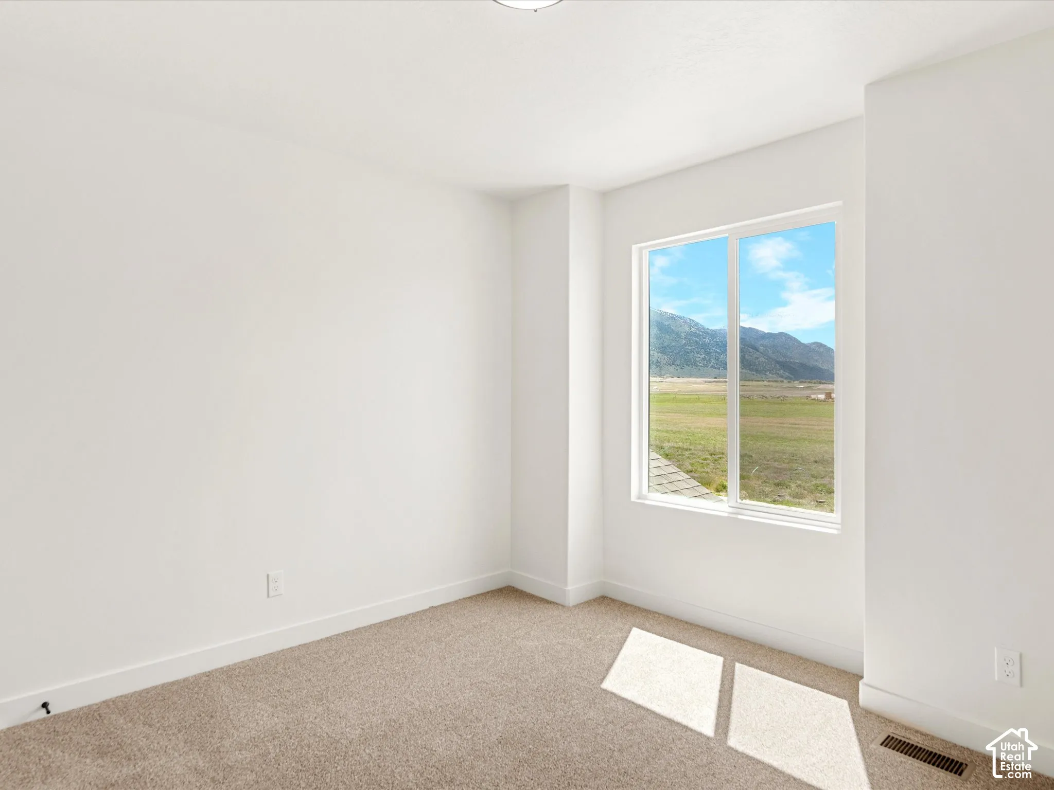 Neutral wall finish, carpeted flooring, and a large window with a natural landscape