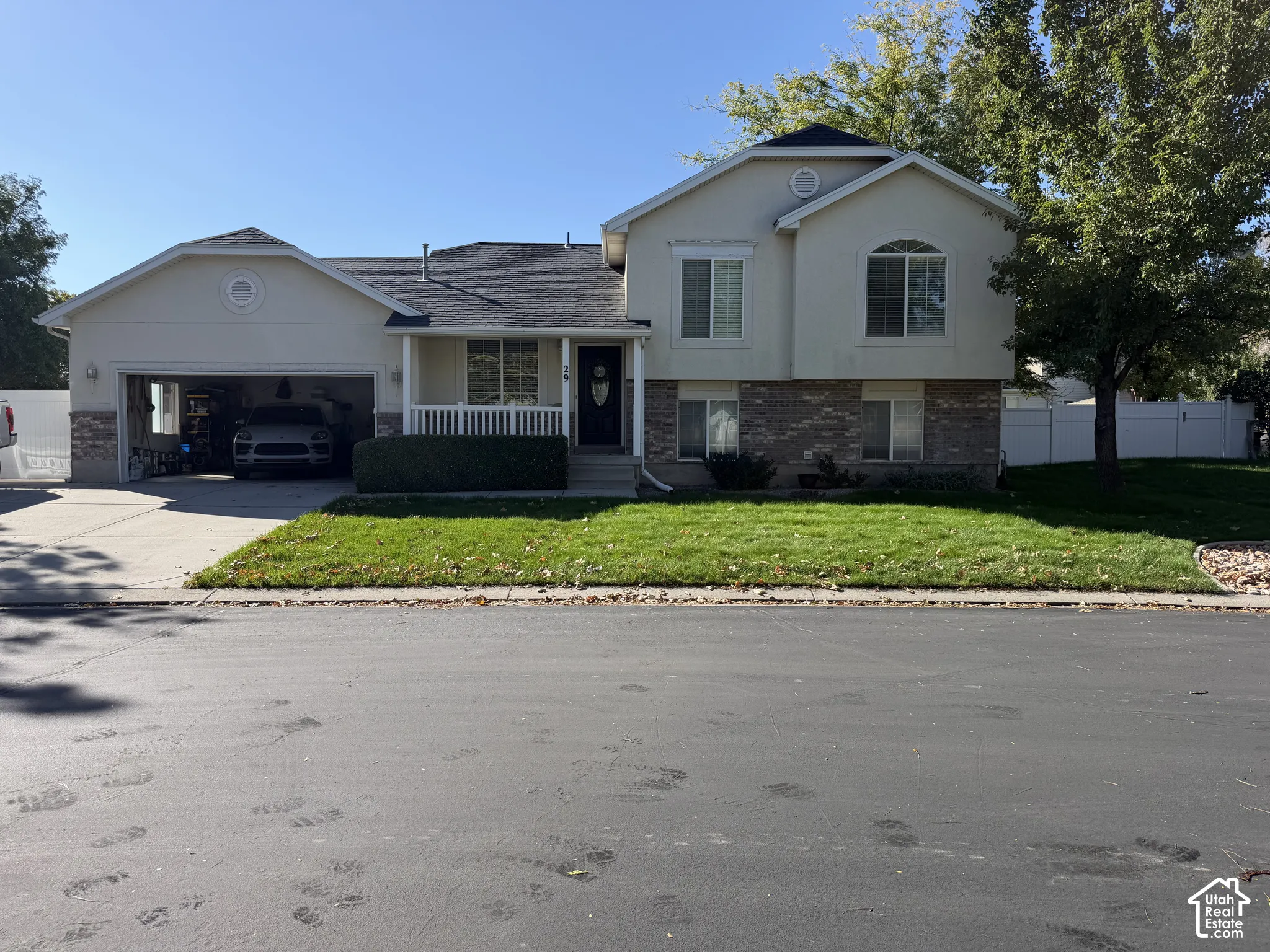 Two-story stucco and stone-finish exterior with an attached two-car garage, covered porch, and front lawn