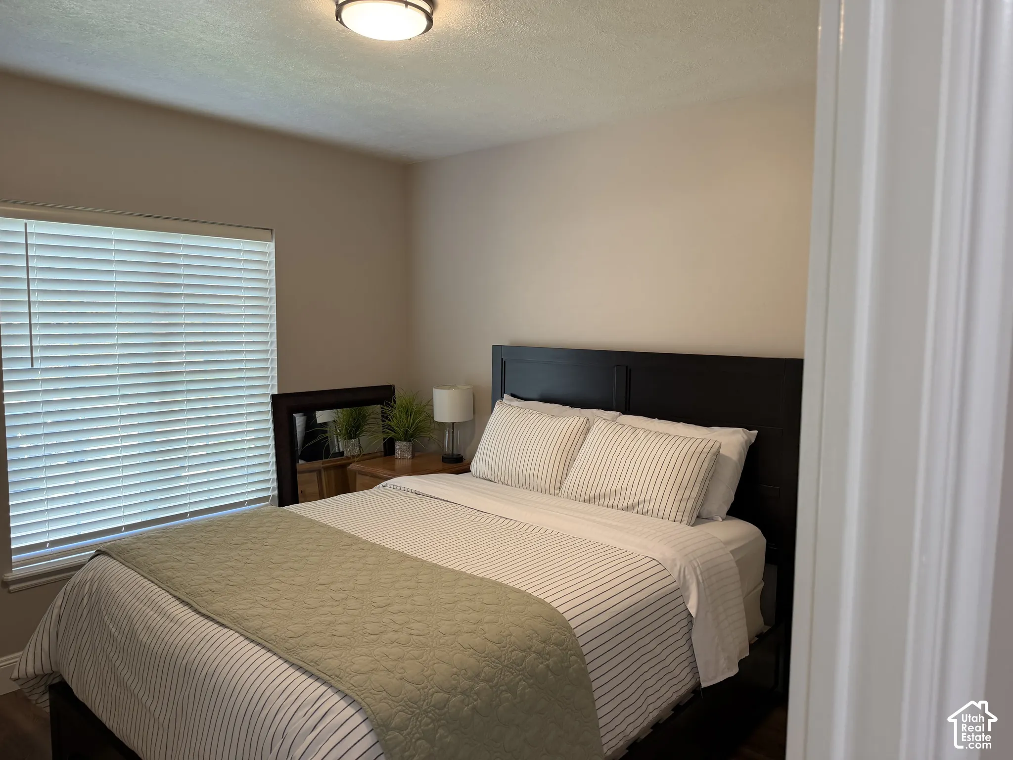 Recessed window with horizontal blinds, wood-finish flooring, and a flush-mount ceiling light fixture