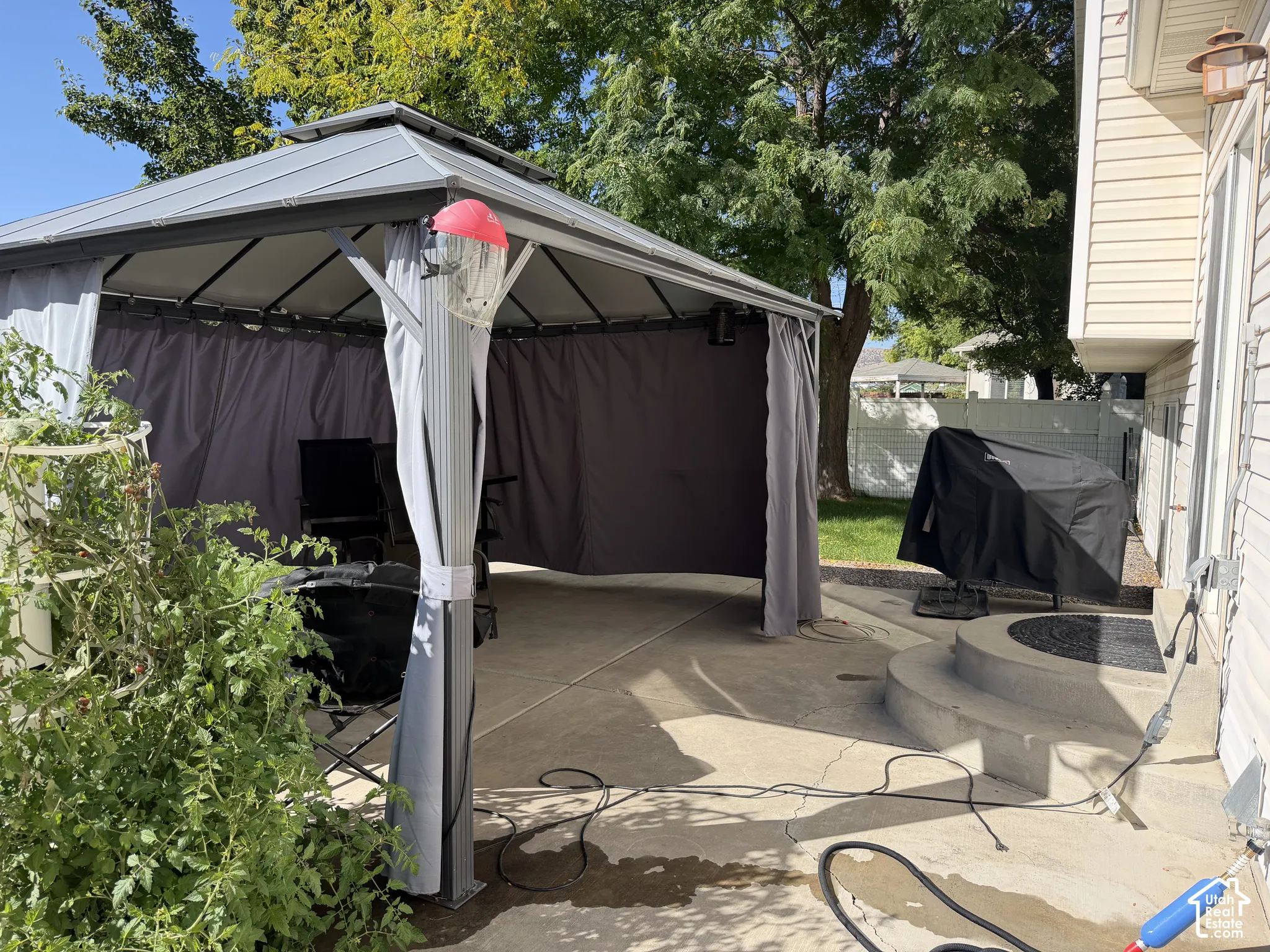Poured concrete patio featuring a metal-frame gazebo with privacy screens, and a multi-level concrete step