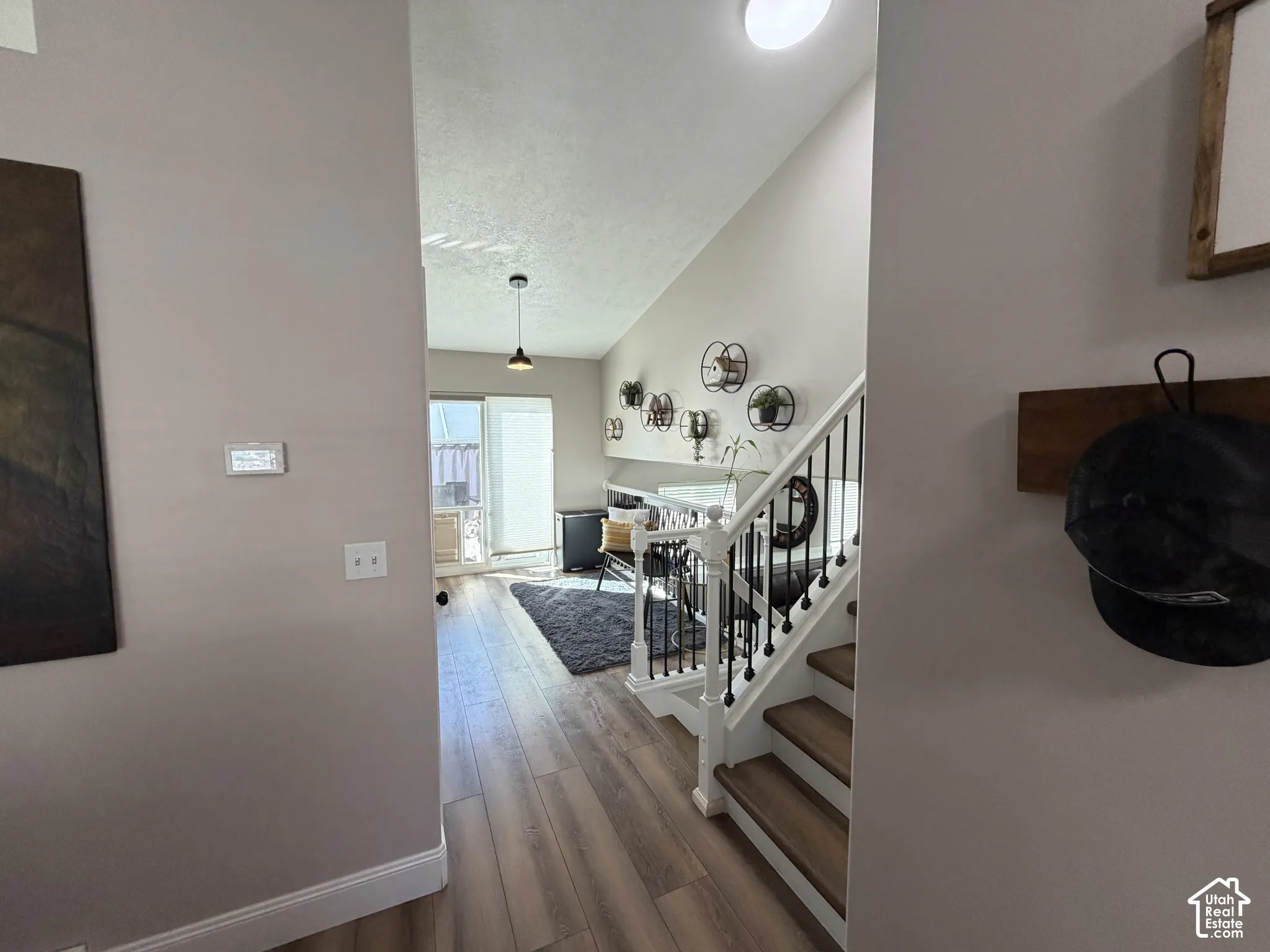 Wood-finish flooring, white baseboards, and a staircase with white risers and black balusters