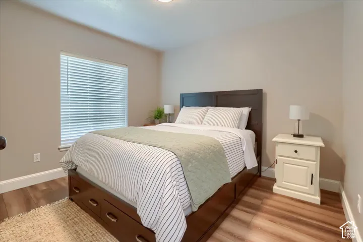 Wood-finish flooring with white baseboards, a window with blinds, and recessed lighting