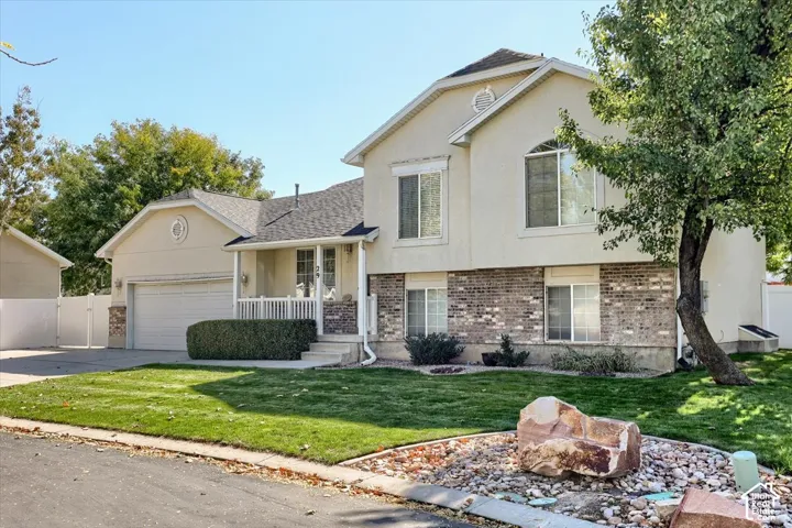 Two-story facade with stucco and brick accents, covered front porch, attached garage, and a manicured lawn