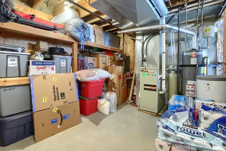 Basement utility area featuring a furnace, water heater, and exposed ceiling joists