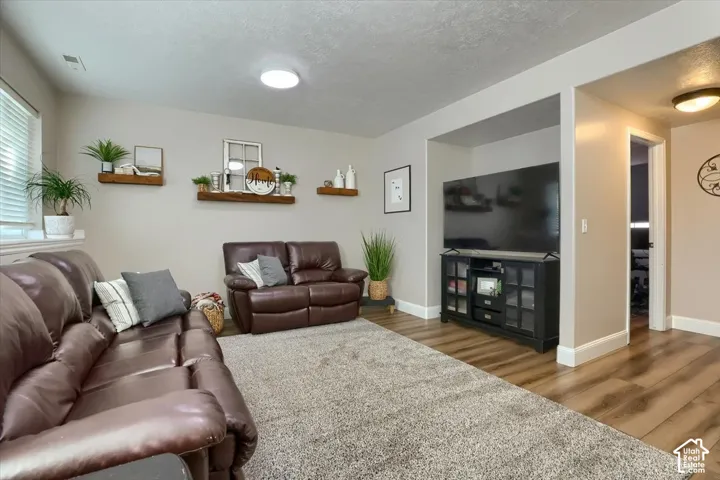 Spacious living area featuring wood-finish flooring, a neutral color palette, and recessed lighting