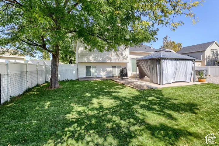 Expansive backyard featuring a large green lawn, mature tree, and white fencing