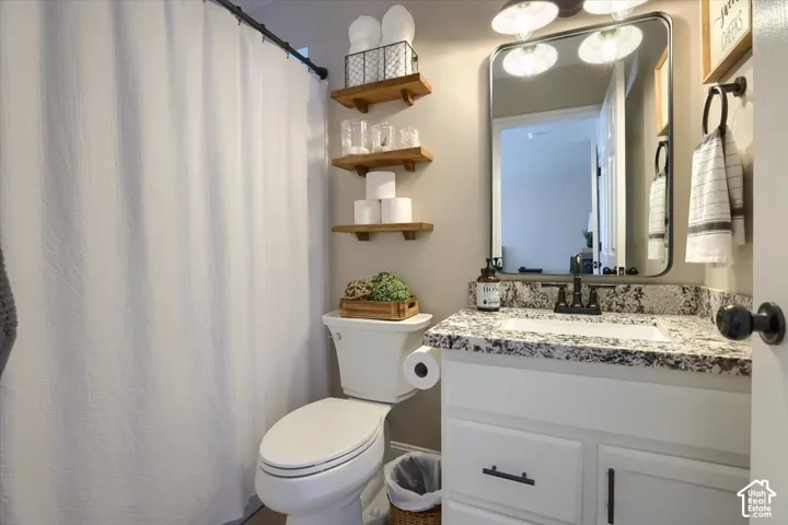 White vanity with a speckled countertop, undermount sink, and matte black faucet