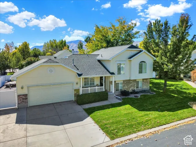 Two-story residence featuring a two-car garage, concrete driveway, and a front porch with white railings