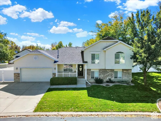 Two-story residence featuring a stone and stucco exterior, an attached two-car garage, and a covered front porch