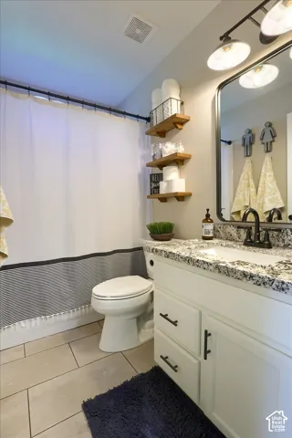 Bathroom featuring a white vanity with dark hardware, a speckled countertop, an undermount sink with a dark faucet, and a large framed mirror