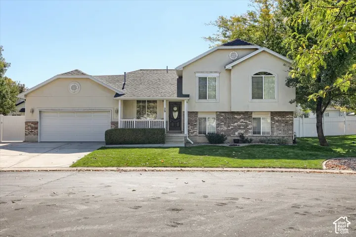 Stucco exterior with brick accenting, covered front porch, attached two-car garage, and established landscaping
