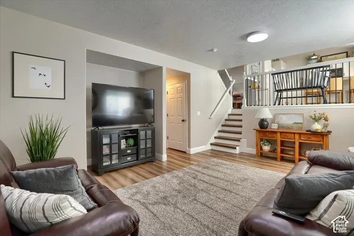Recessed lighting, wood-finish flooring, staircase with white risers and wood treads, white wall paint, and a built-in media console
