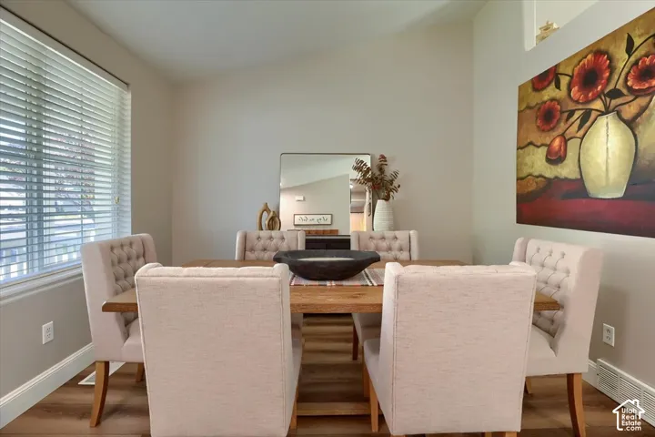 Vaulted ceiling, wood-finish flooring, and window with horizontal blinds