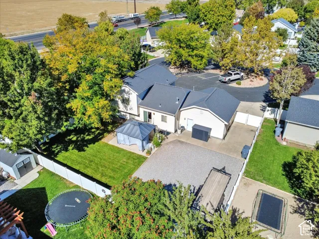 Expansive property featuring a paved driveway, detached garage, white privacy fencing, and a separate storage shed
