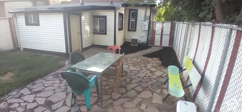 Stone patio area with an integrated paved walkway and chain-link fencing