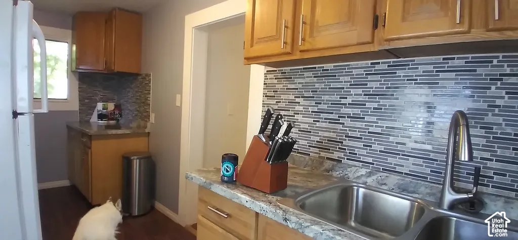 Wood cabinetry, full tile backsplash, double basin stainless steel sink, and wood-finish flooring