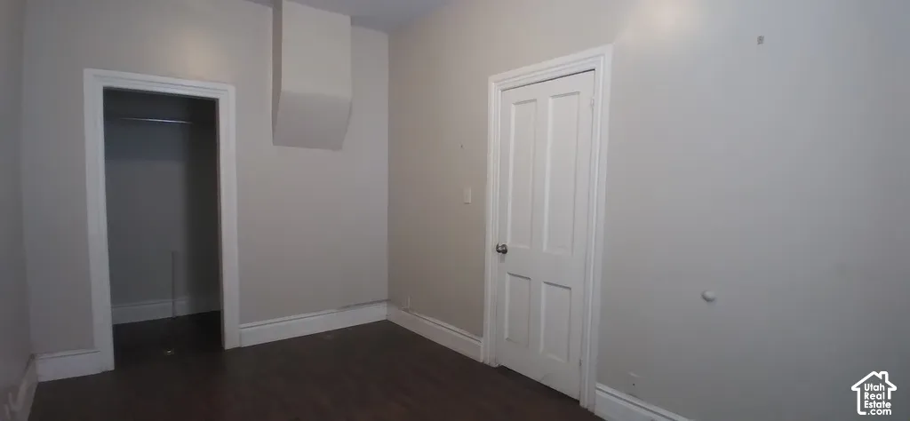 Dark-finish flooring, white trim, recessed closet, and a white paneled door