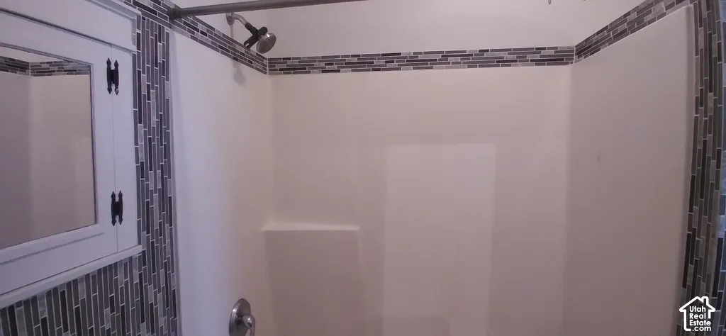 Shower with a white surround, integrated shelf, and mosaic tile accents