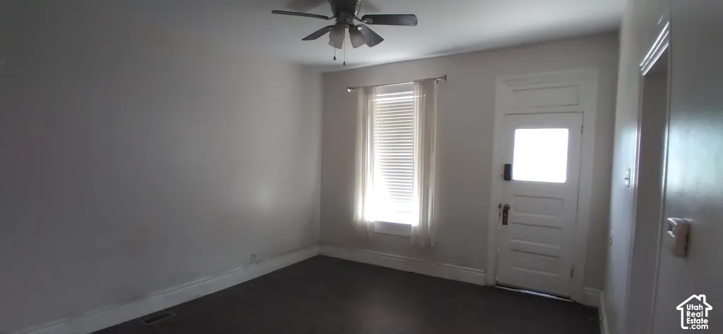Wood-finish flooring, ceiling fan, single window with blinds, white paneled door with glass insert, and white trim