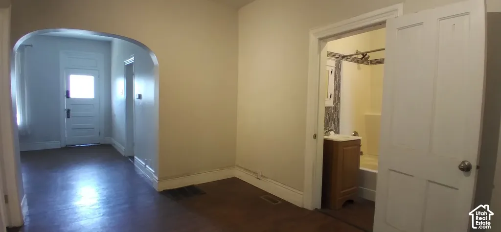 Arched doorway entry to an interior space with wood-finish flooring