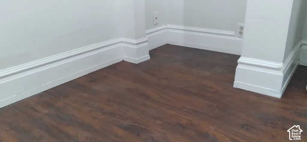 Wood-finish flooring with white baseboard and wall trim