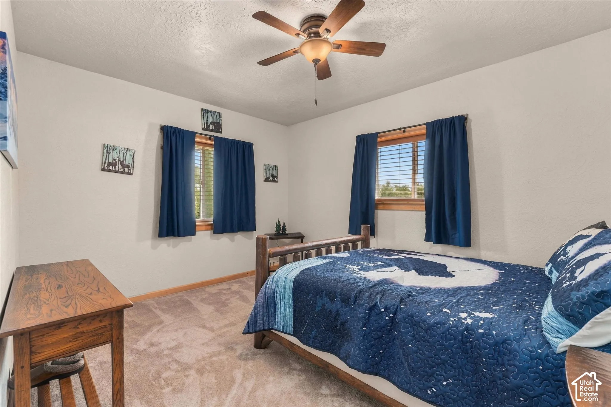 Soft carpet flooring, two windows with wood trim, ceiling fan light fixture, and neutral wall tones