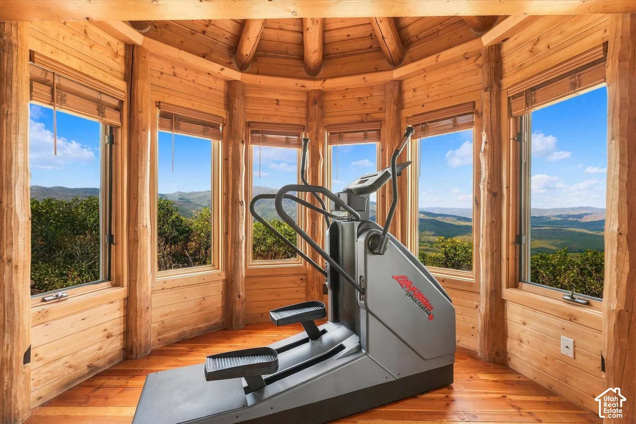 Curved room featuring extensive wood paneling and log-style structural beams
