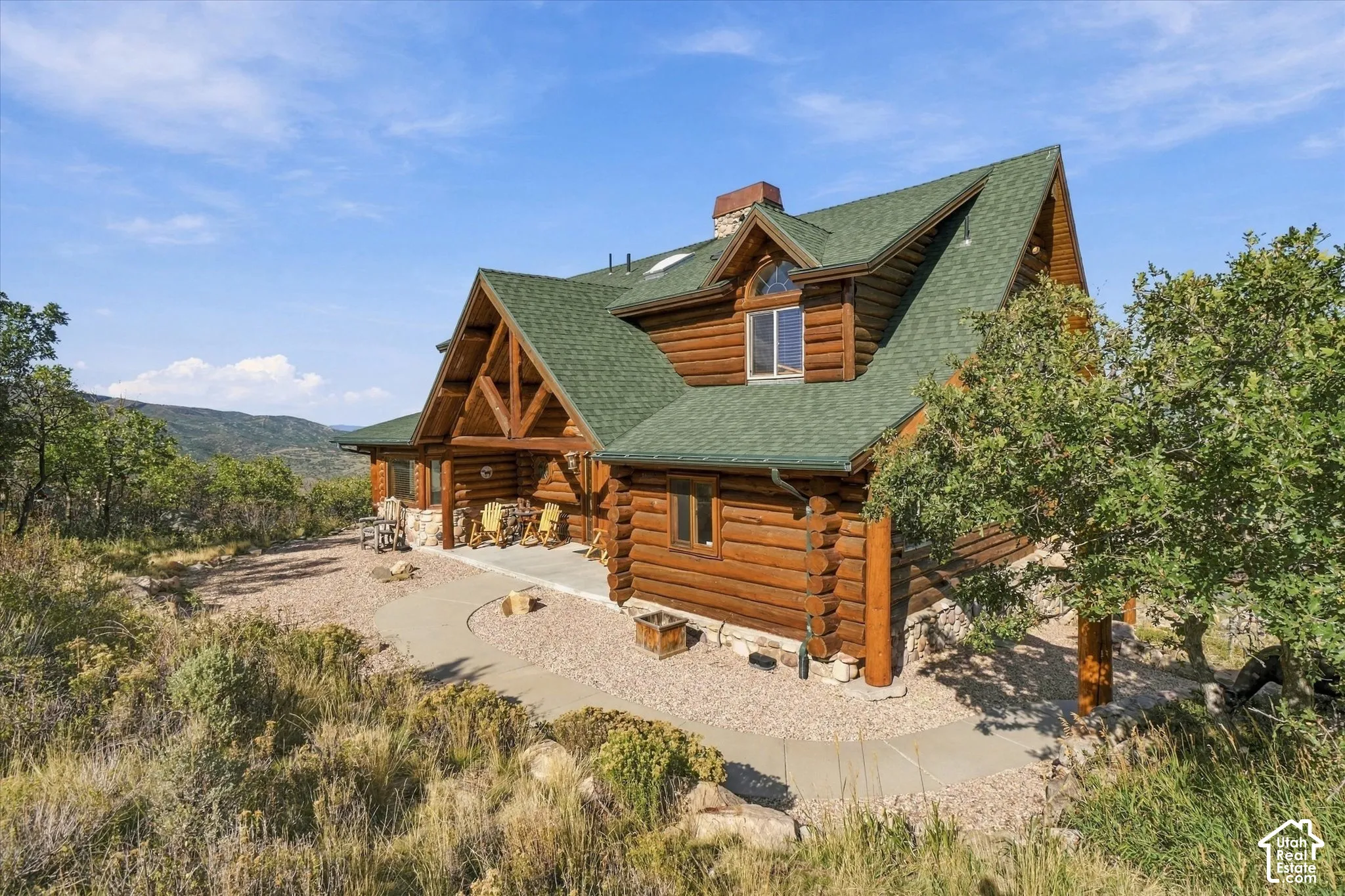 Log home featuring a green shingle roof, stone foundation, and wood siding