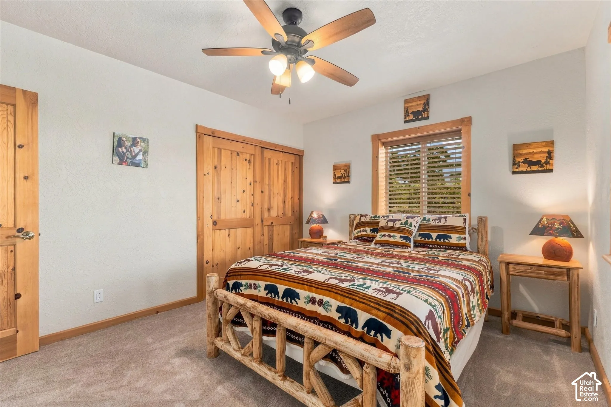 Carpeted bedroom featuring a ceiling fan with integrated lighting, wood-finish bi-fold closet doors, and a wood-framed window with blinds